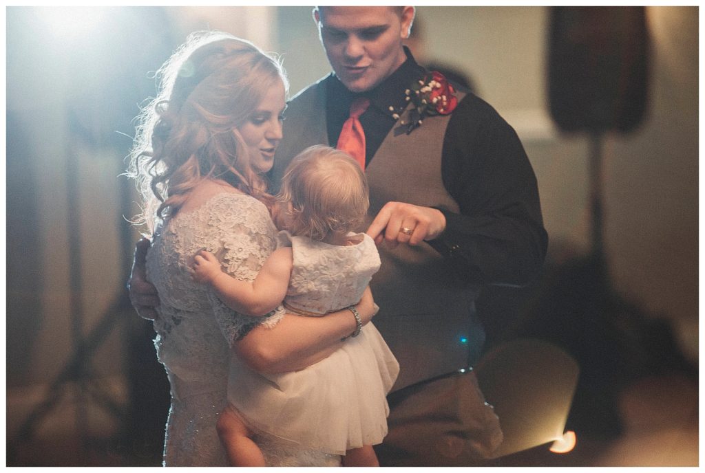 bride and groom dancing with their daughter