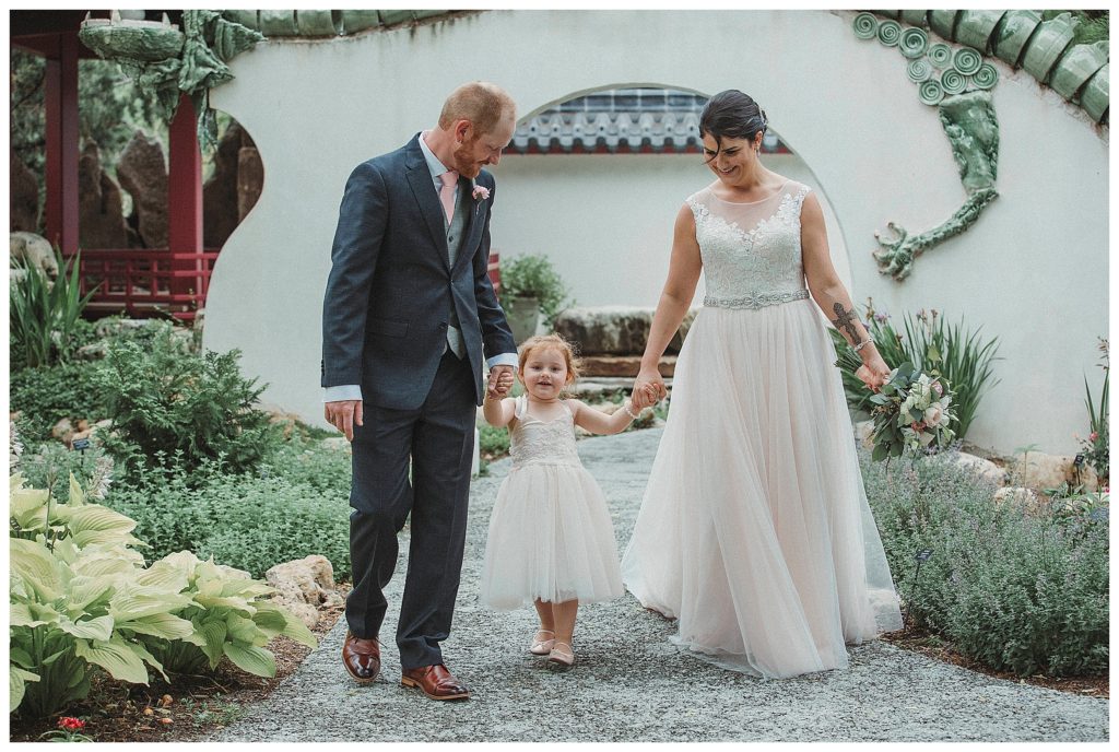 bride and groom walking with the flower girl