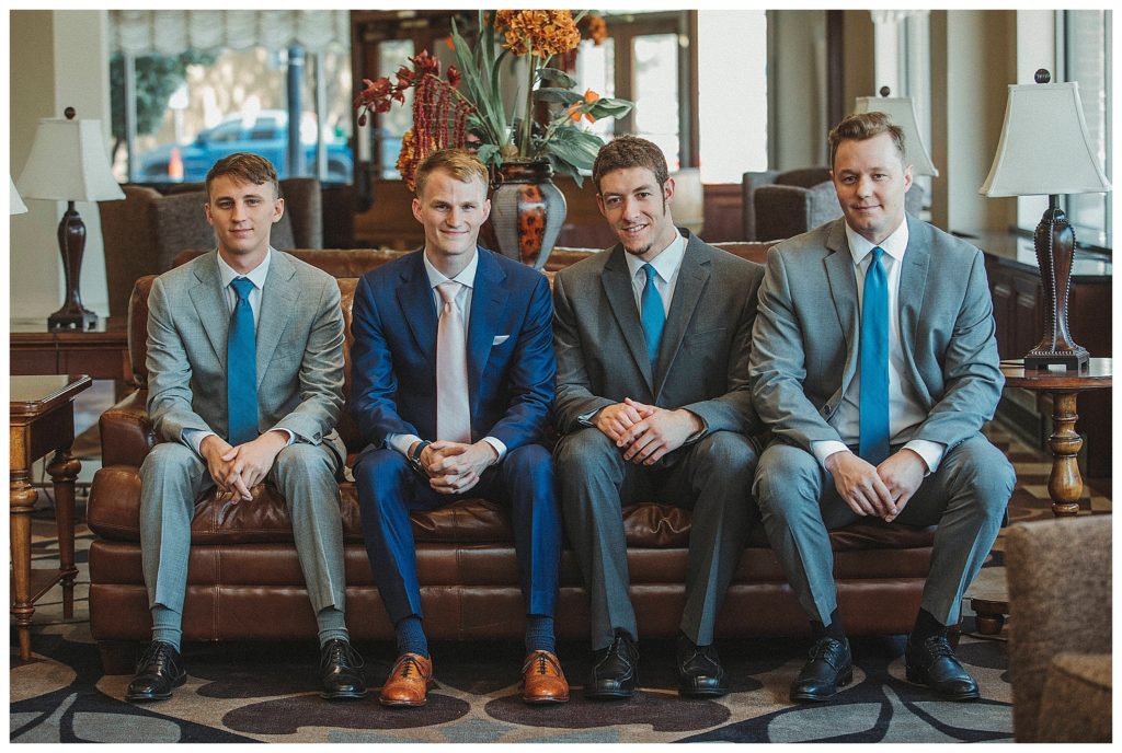 groom and groomsmen sitting on hotel lobby couch