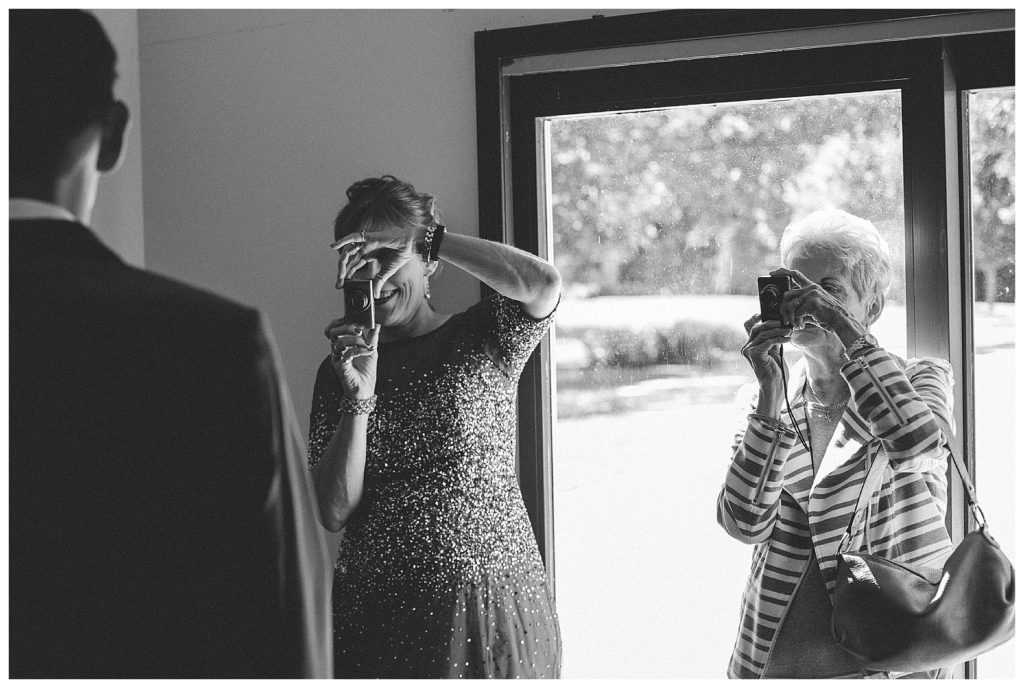 mother and grandmother taking pictures of groom