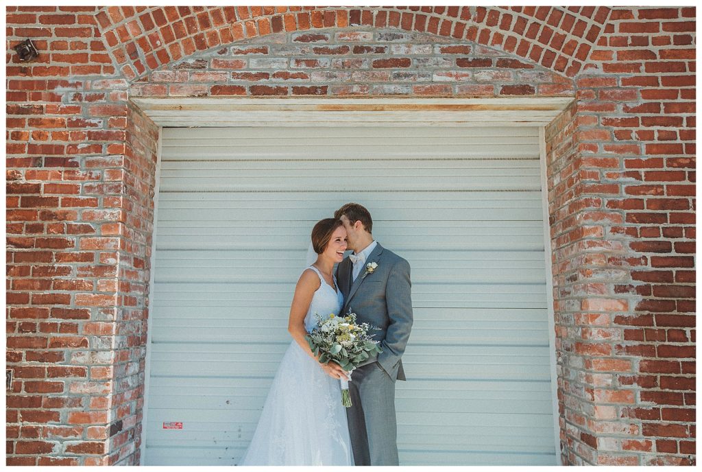 bride and groom in front of white building