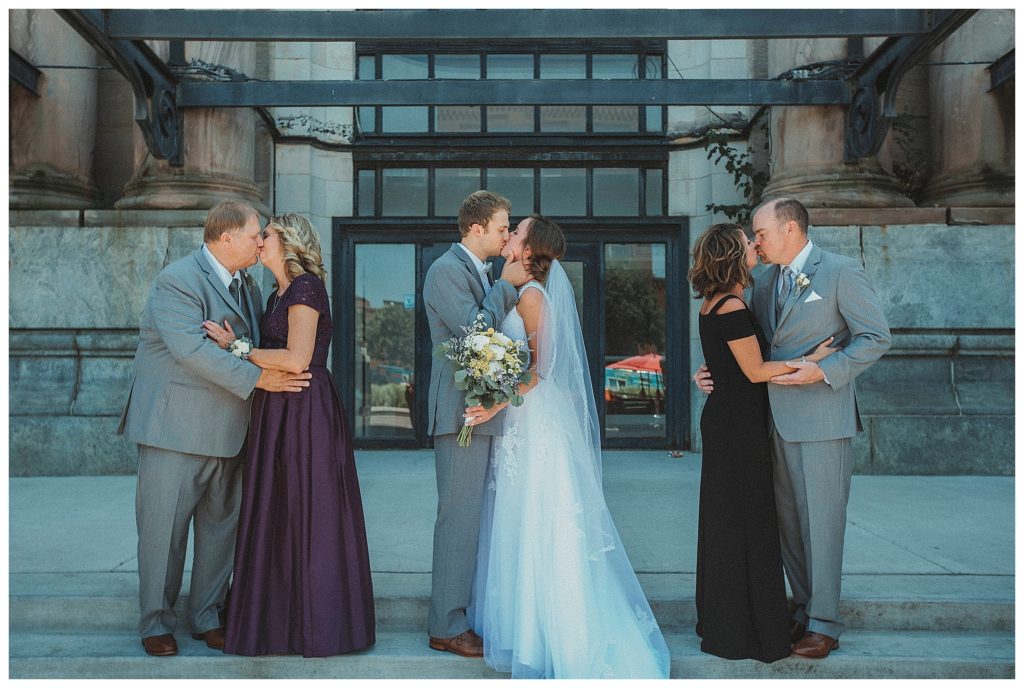 groom kissing his bride with parents kissing
