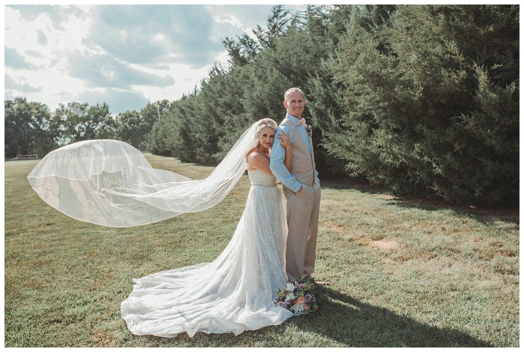 bride and groom with veil flowing in breeze