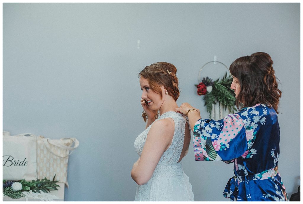 brides mother helping her in wedding dress