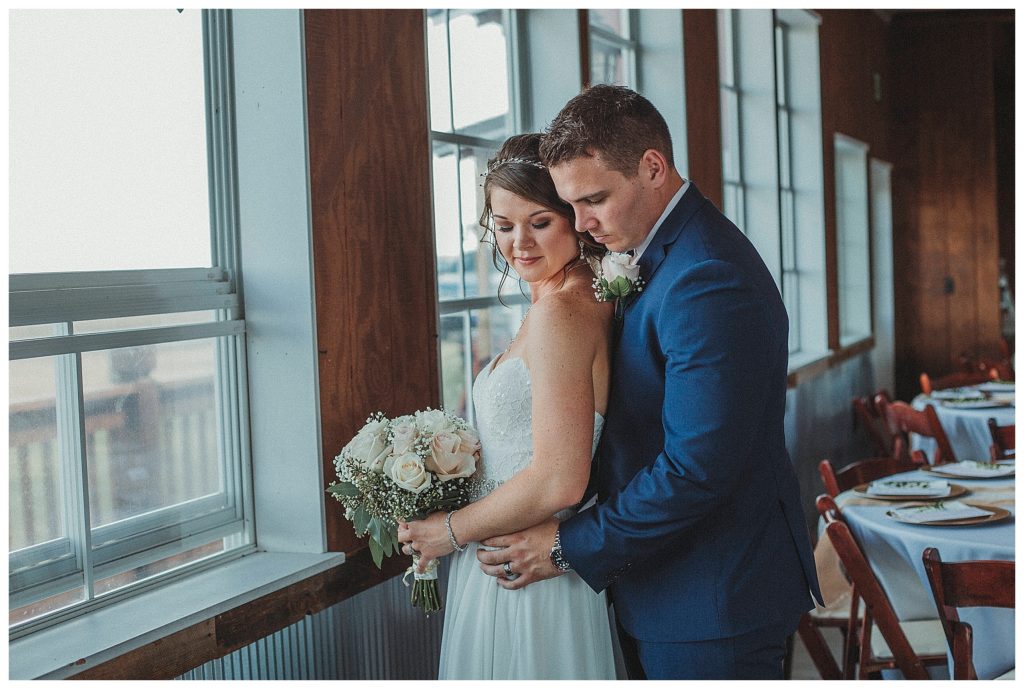 groom holding his bride near window