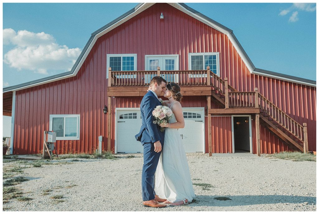 bride and groom in front of barn