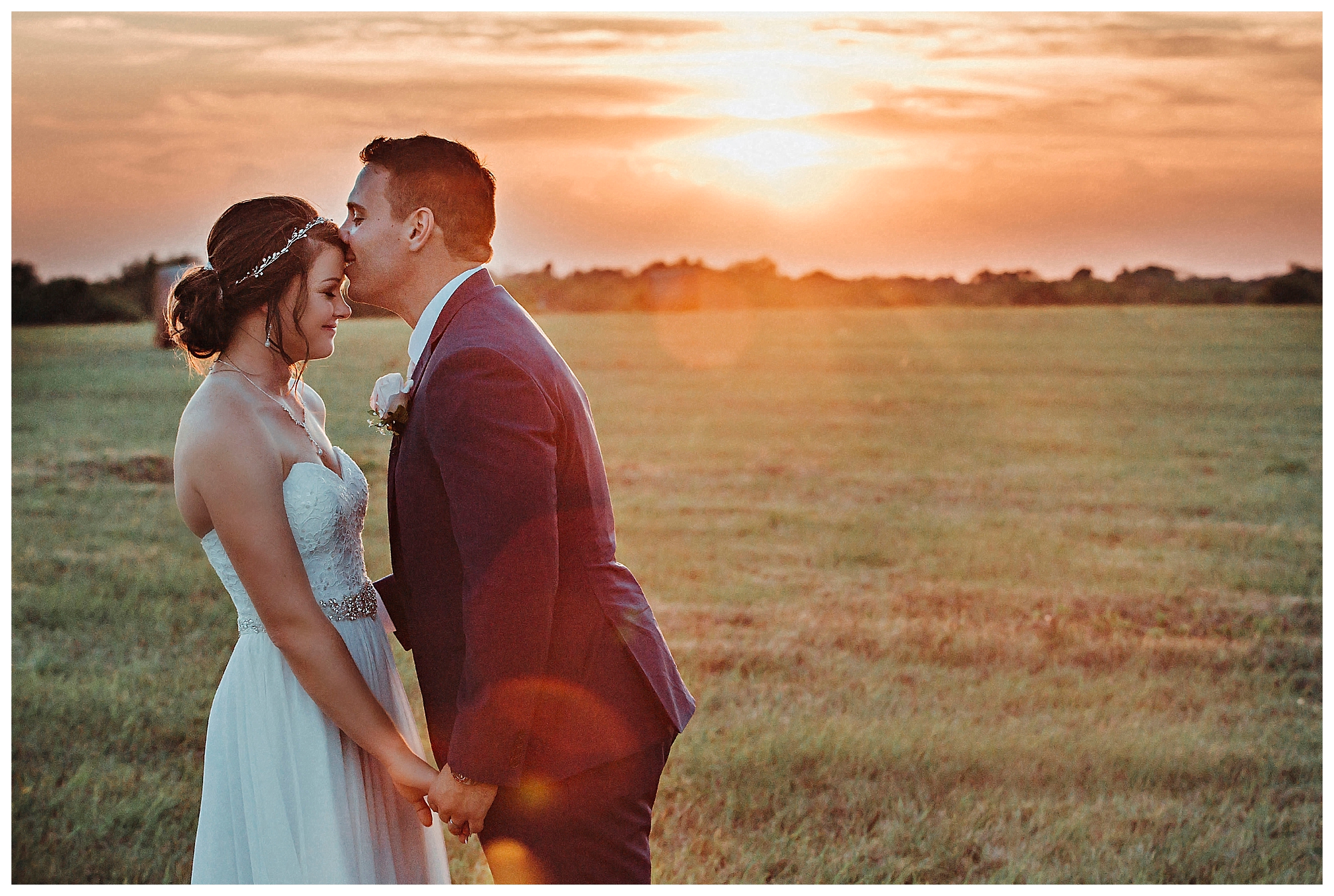 groom kissing bride on forehead at sunset