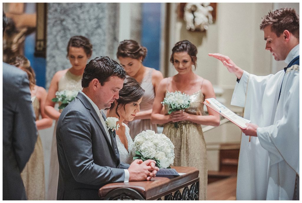 bride and groom kneeling at the alter