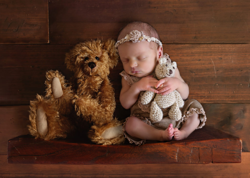 baby sitting on shelf next to brown bear