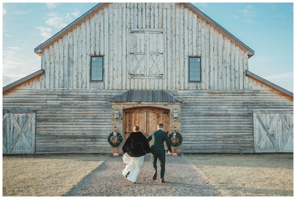 bride and groom running back to barn