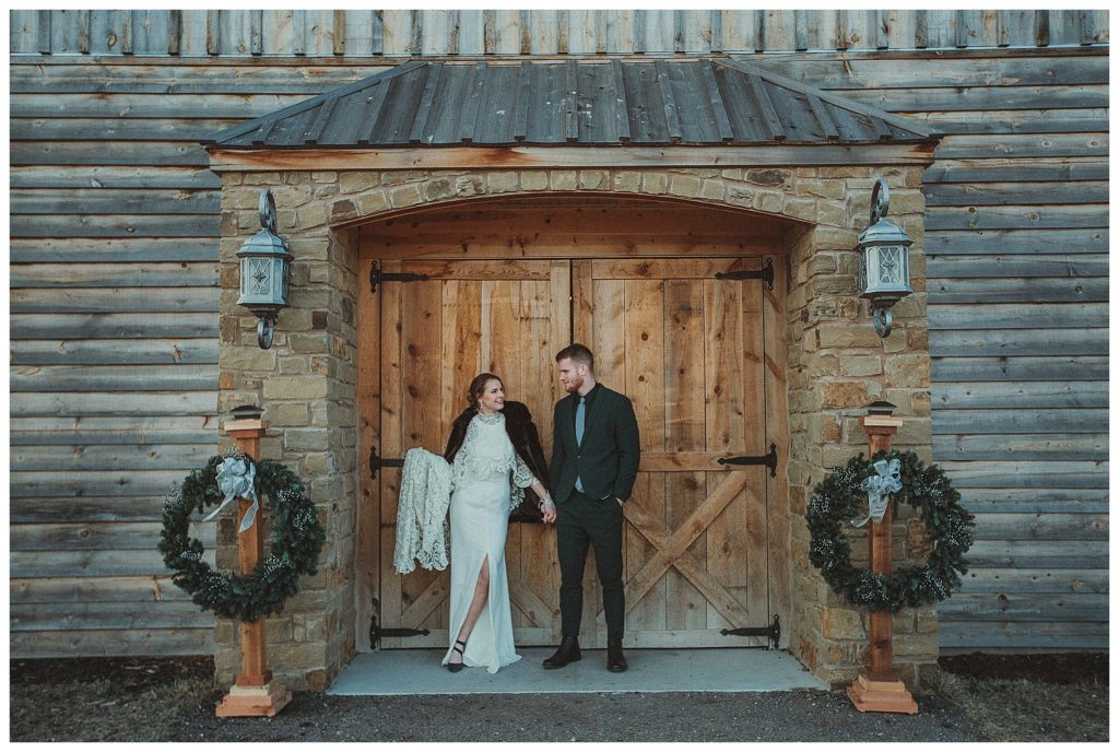 bride and groom standing in front of barn