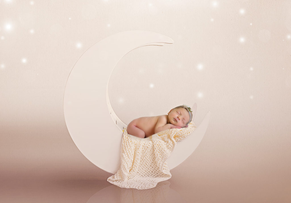 baby girl laying on white moon