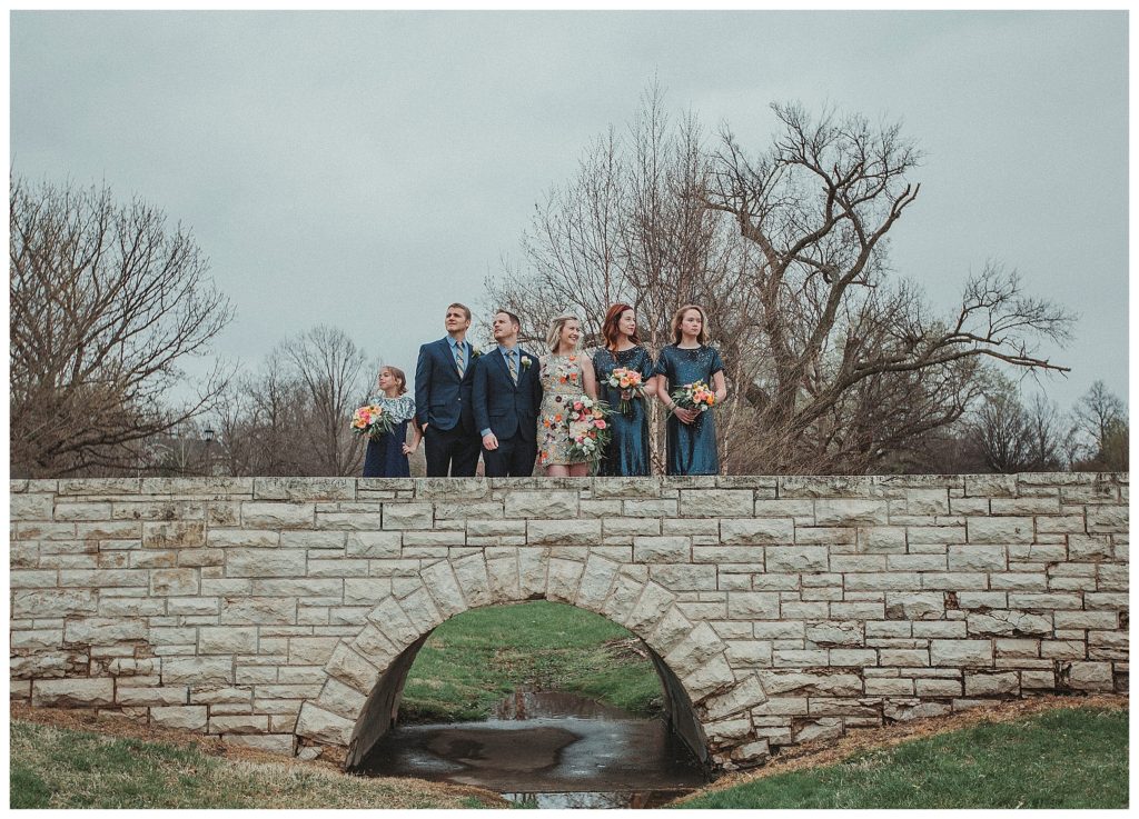 bridal party standing on a stone bridge
